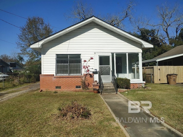 bungalow featuring brick siding, entry steps, crawl space, fence, and a front lawn