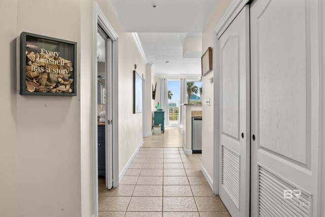 hall with crown molding and light tile patterned flooring