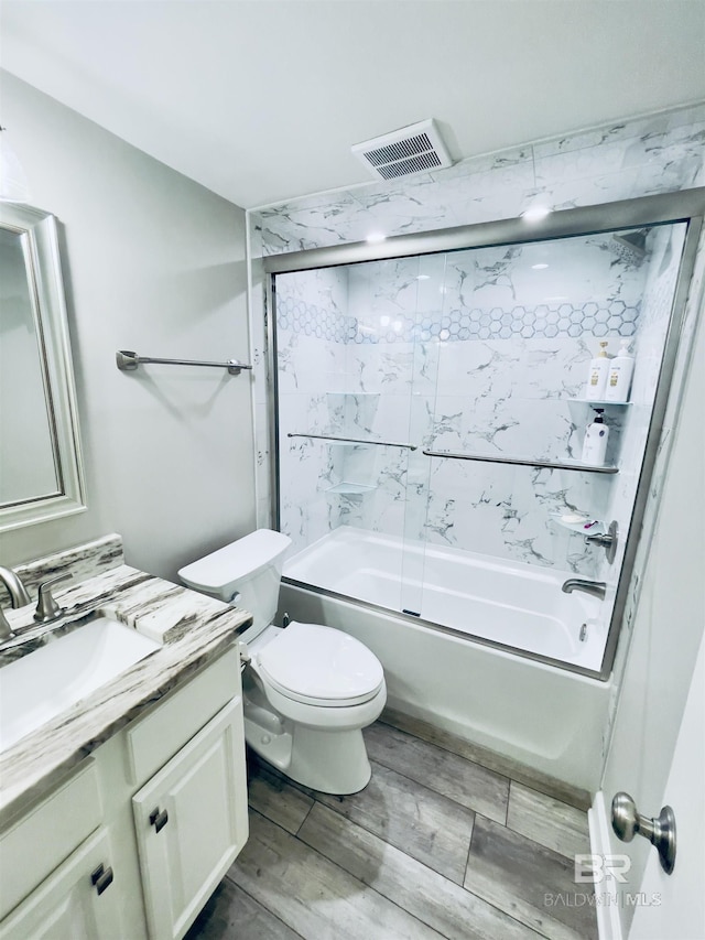 full bathroom featuring toilet, wood-type flooring, vanity, and bath / shower combo with glass door