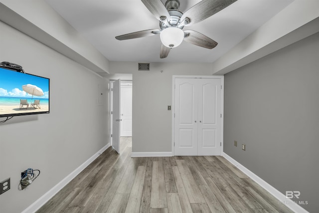 unfurnished bedroom with ceiling fan, light wood-type flooring, and a closet