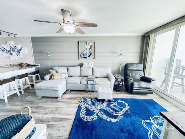 living room with light wood-type flooring, crown molding, and ceiling fan