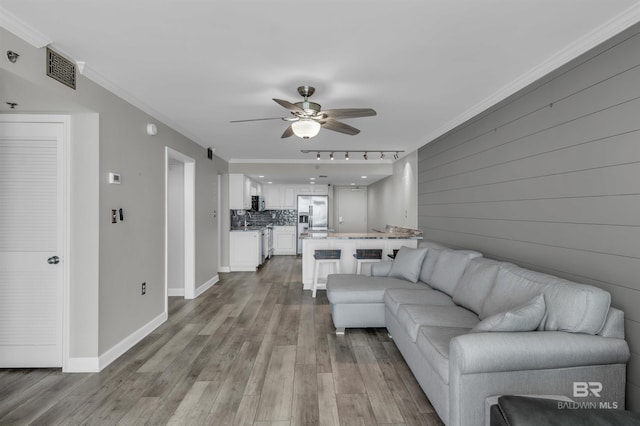 living room with ceiling fan, light hardwood / wood-style floors, and crown molding