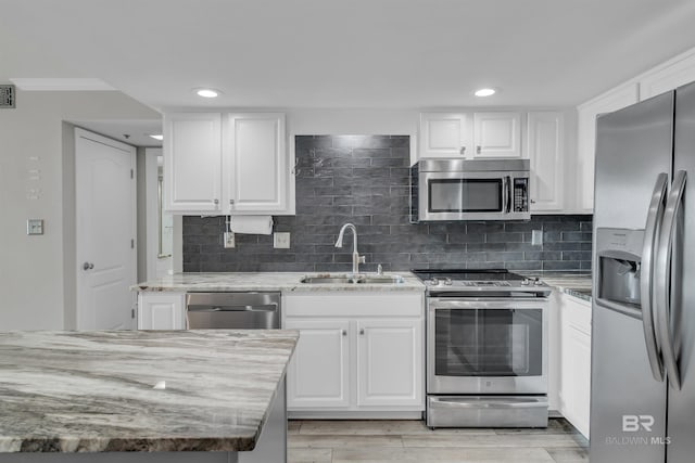 kitchen with light hardwood / wood-style flooring, appliances with stainless steel finishes, sink, white cabinets, and light stone countertops