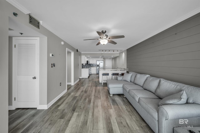 living room featuring light hardwood / wood-style flooring, ceiling fan, and ornamental molding