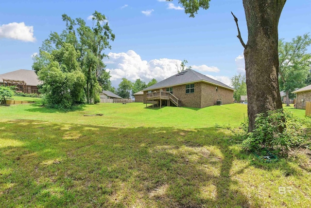 view of grassy yard with stairway and a wooden deck