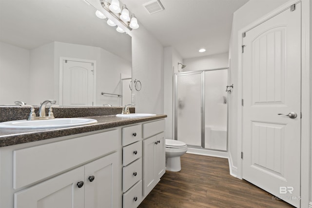 full bathroom with a shower stall, double vanity, wood finished floors, toilet, and recessed lighting
