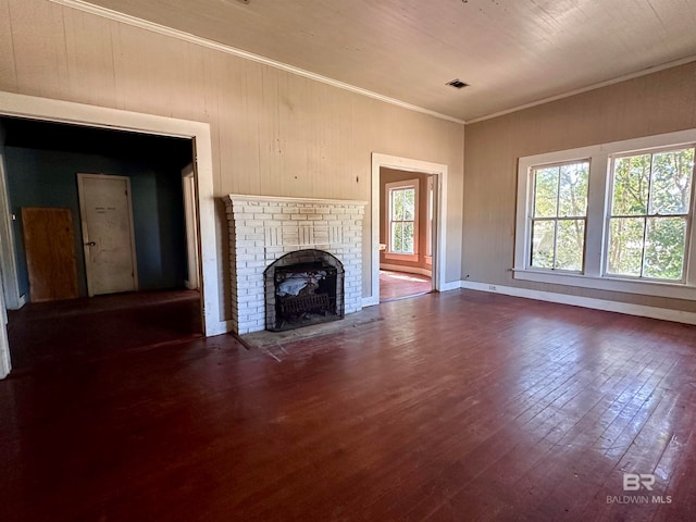 unfurnished living room with ornamental molding, dark hardwood / wood-style floors, wooden walls, and a fireplace