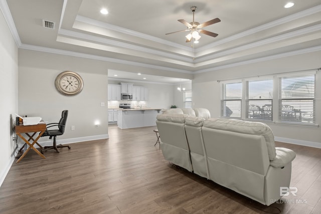 living room with dark hardwood / wood-style flooring, a raised ceiling, ceiling fan, and ornamental molding