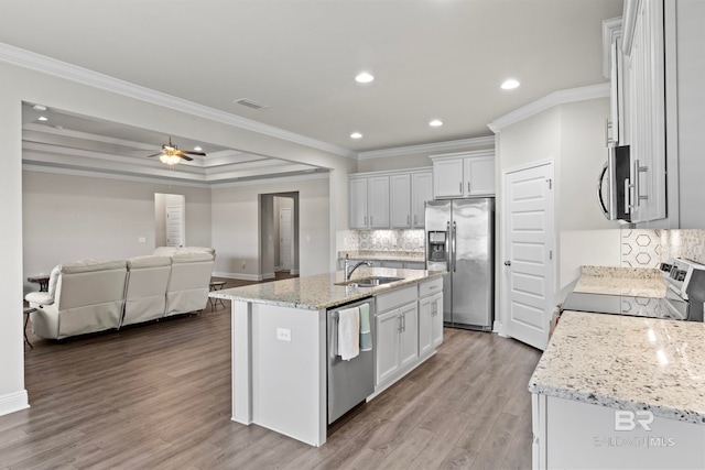 kitchen featuring ornamental molding, an island with sink, appliances with stainless steel finishes, light hardwood / wood-style floors, and white cabinetry