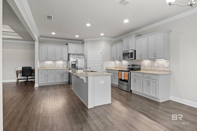 kitchen featuring a kitchen island with sink, ornamental molding, dark hardwood / wood-style flooring, light stone counters, and stainless steel appliances