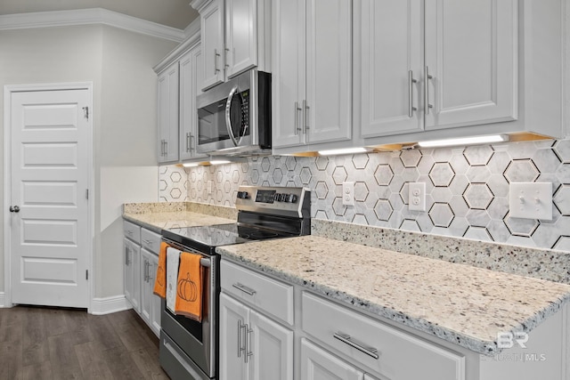 kitchen with light stone countertops, dark hardwood / wood-style flooring, backsplash, crown molding, and appliances with stainless steel finishes