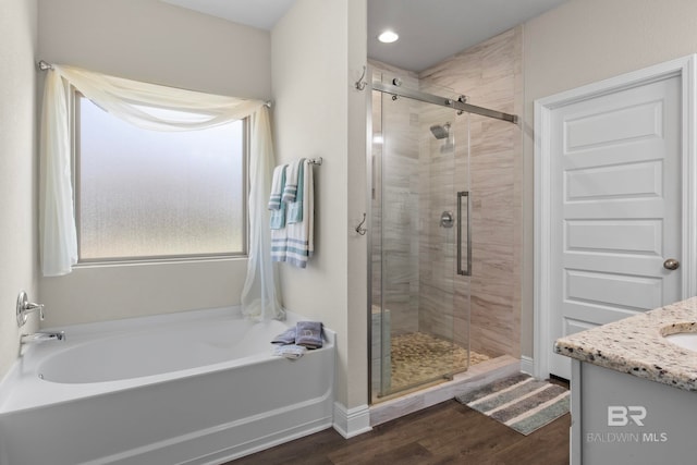 bathroom featuring hardwood / wood-style floors, vanity, and shower with separate bathtub