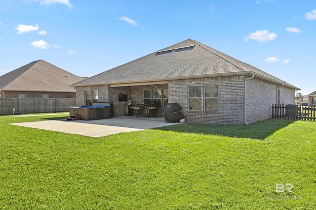 rear view of house featuring a patio, a hot tub, and a lawn