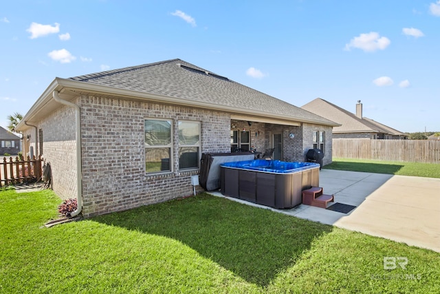 rear view of house featuring a patio area, a yard, and a hot tub