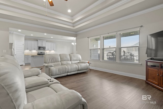 living room featuring a raised ceiling, crown molding, ceiling fan, and hardwood / wood-style flooring