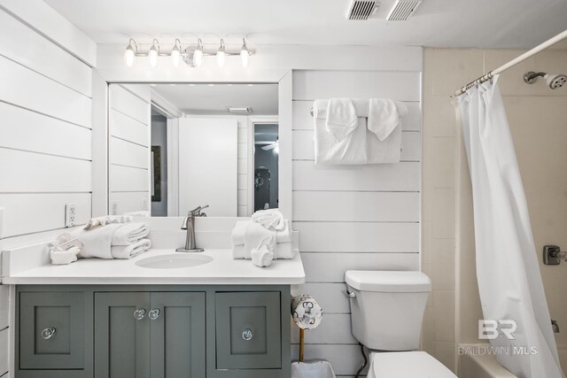 full bathroom featuring vanity, toilet, wooden walls, and shower / tub combo with curtain