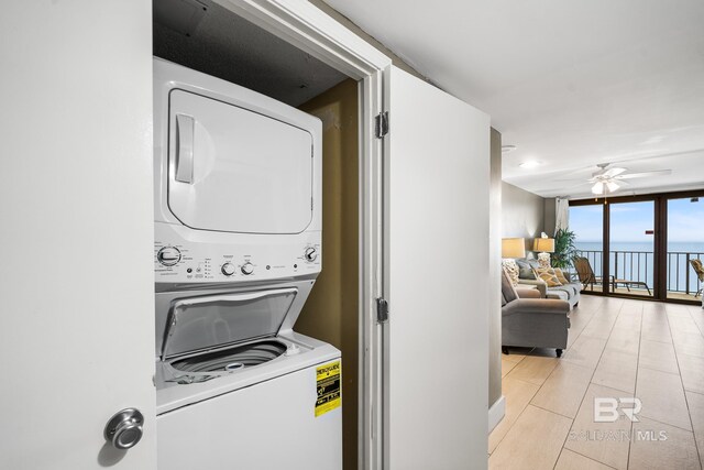 laundry room with ceiling fan, stacked washer and dryer, and light tile patterned flooring