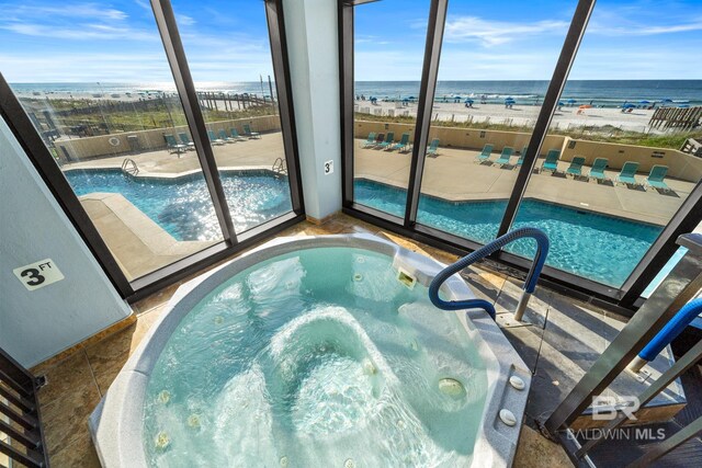 view of pool featuring a water view and a beach view