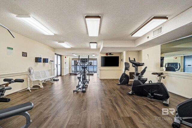 workout area featuring dark hardwood / wood-style flooring and a textured ceiling