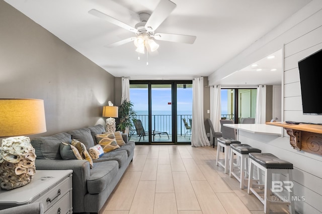 living room featuring ceiling fan and expansive windows