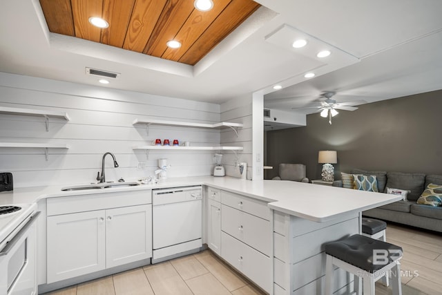 kitchen with ceiling fan, sink, kitchen peninsula, white appliances, and white cabinets