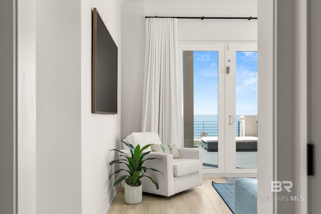 sitting room with a wealth of natural light, light hardwood / wood-style flooring, and french doors