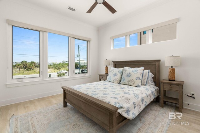 bedroom featuring ceiling fan, light wood-type flooring, and crown molding