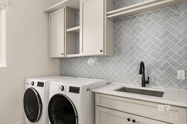 laundry room featuring sink, independent washer and dryer, and cabinets