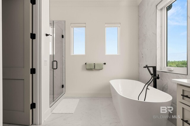 bathroom featuring a wealth of natural light, tile patterned floors, plus walk in shower, and vanity