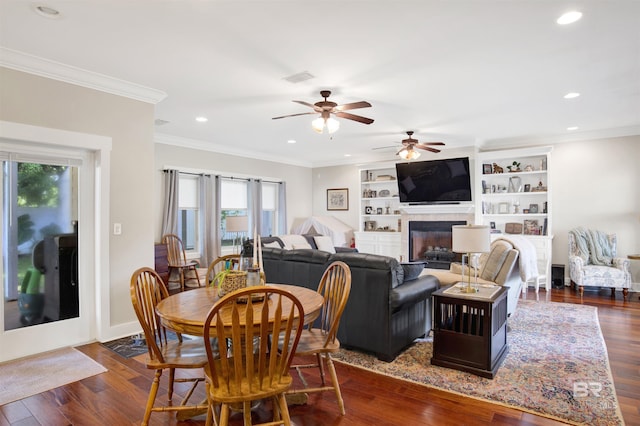 17541 Council Oaks Ln, Bon Secour, AL 36511 - dining area with ceiling fan, a glass covered fireplace, dark wood finished floors, recessed lighting, and ornamental molding