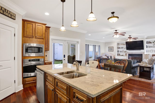 17541 Council Oaks Ln, Bon Secour, AL 36511 - kitchen featuring appliances with stainless steel finishes, ceiling fan, dark wood finished floors, ornamental molding, and a kitchen island with sink