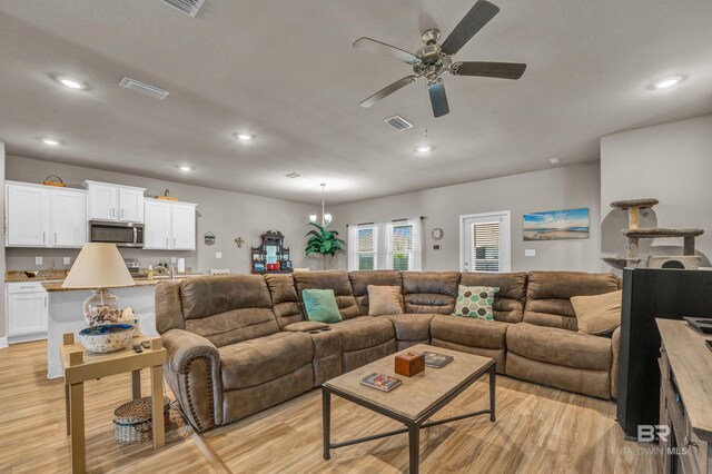 living room with ceiling fan, light wood-style floors, recessed lighting, and a chandelier