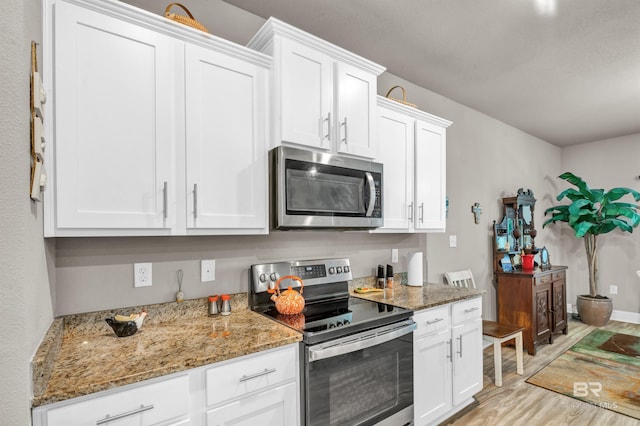 kitchen with appliances with stainless steel finishes, light wood-style flooring, and white cabinets