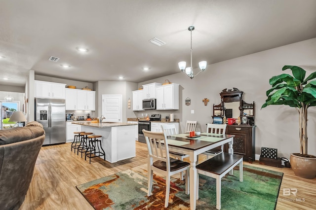 dining space with light wood finished floors, recessed lighting, and a chandelier
