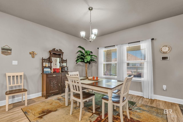 dining room with light wood-type flooring, a chandelier, and baseboards