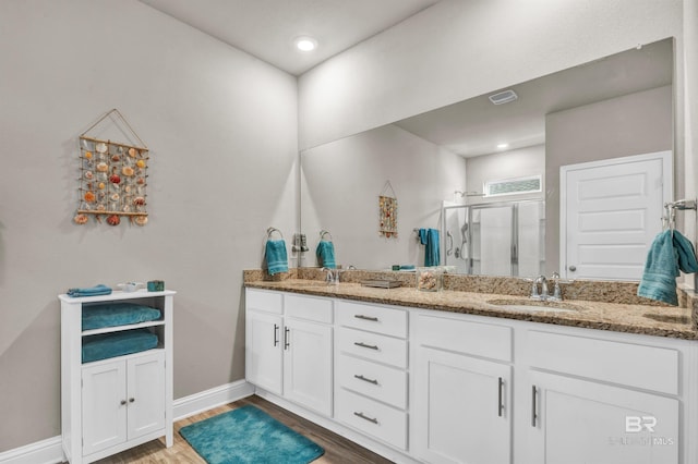 full bath with a shower stall, wood finished floors, double vanity, baseboards, and recessed lighting