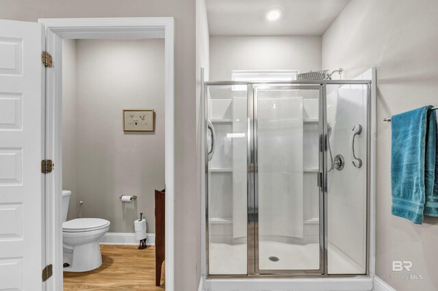 full bath with a shower stall, toilet, wood finished floors, and baseboards