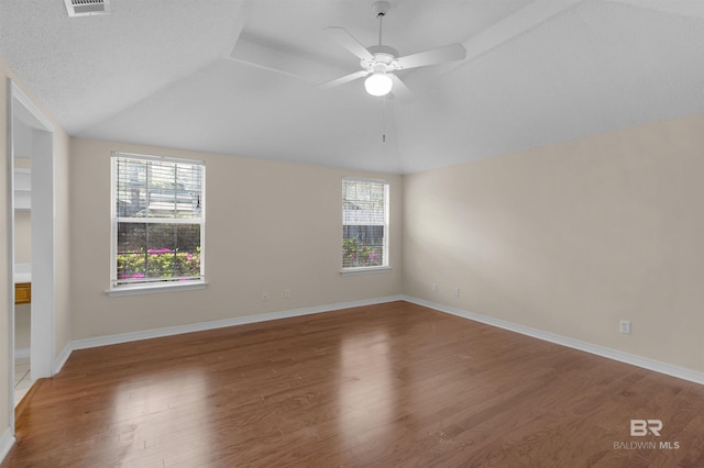 unfurnished room featuring lofted ceiling, plenty of natural light, and wood finished floors