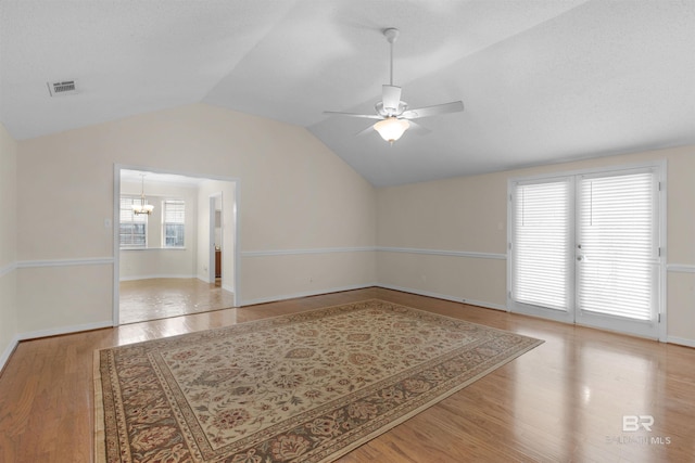 unfurnished room featuring light wood-style floors, ceiling fan with notable chandelier, visible vents, and a healthy amount of sunlight