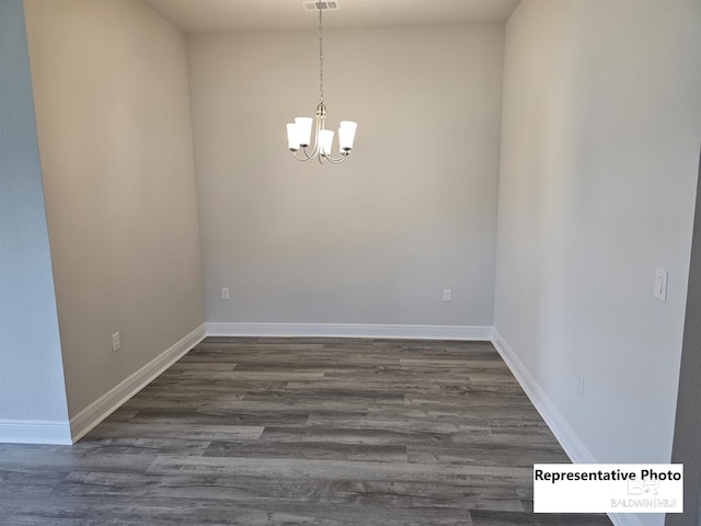 empty room featuring dark hardwood / wood-style floors and a chandelier