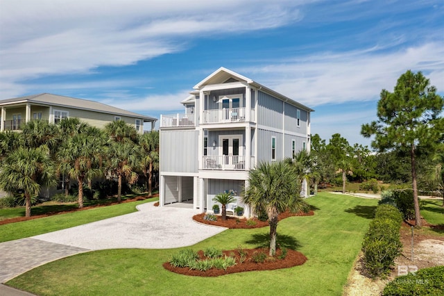 view of front facade with a balcony, french doors, and a front lawn