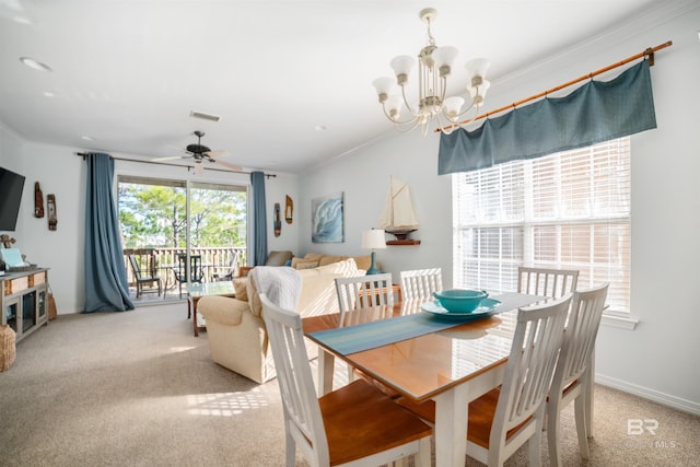 carpeted dining room with ceiling fan with notable chandelier, a wealth of natural light, and ornamental molding