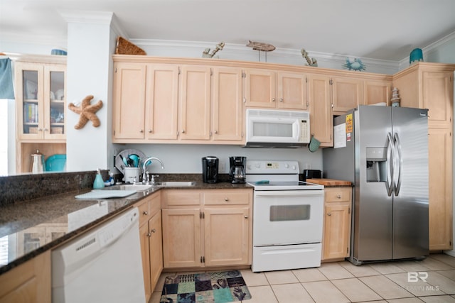 kitchen featuring white appliances, crown molding, light tile patterned floors, sink, and dark stone countertops