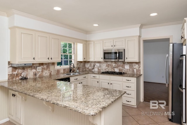 3755 N Claridge Rd, Mobile, AL 36608 - kitchen featuring appliances with stainless steel finishes, a sink, a peninsula, light stone countertops, and a kitchen bar