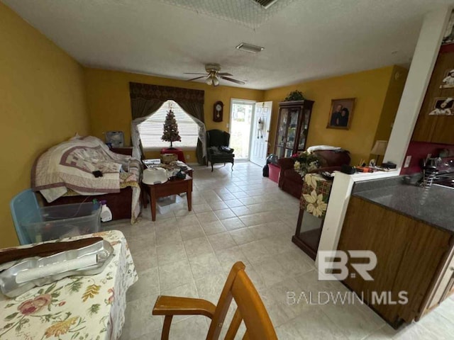 living area with light tile patterned floors, visible vents, and a ceiling fan