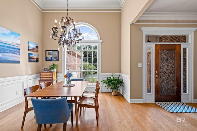 9791 Aspen Cir, Spanish Fort, AL 36527 - dining room featuring a chandelier, crown molding, light wood-style floors, a wainscoted wall, and a decorative wall