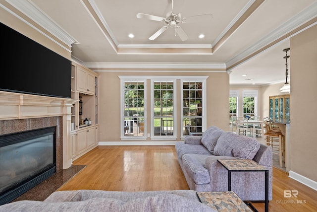 9791 Aspen Cir, Spanish Fort, AL 36527 - living area with light wood-style flooring, a fireplace, ornamental molding, a ceiling fan, and a raised ceiling