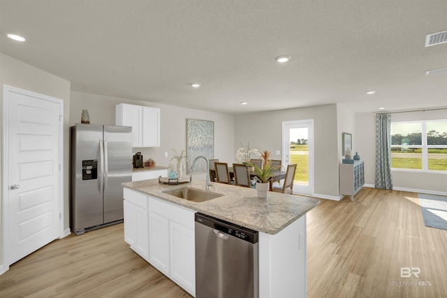 kitchen featuring sink, appliances with stainless steel finishes, a kitchen island with sink, white cabinetry, and light stone countertops