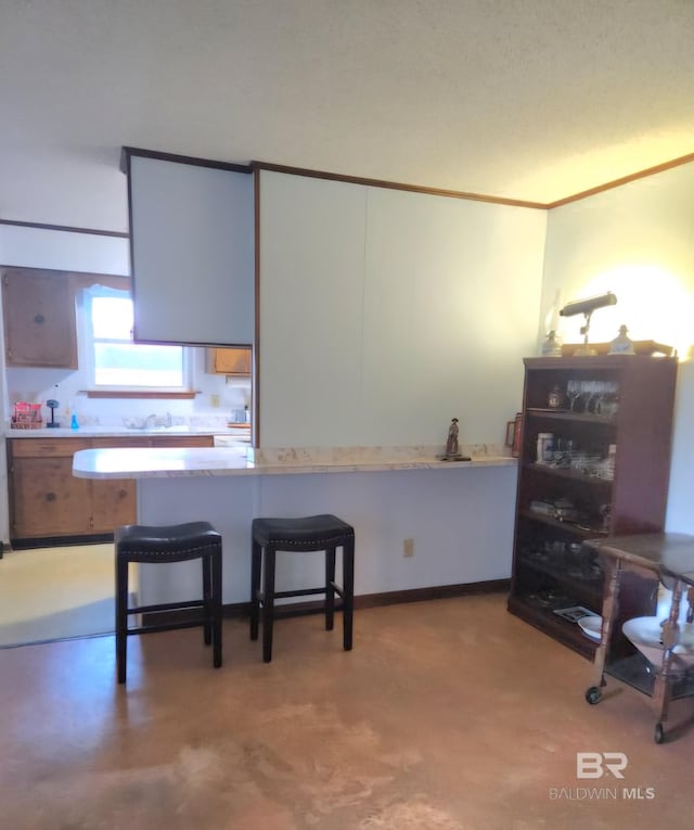 kitchen with white cabinetry, crown molding, kitchen peninsula, and a kitchen bar