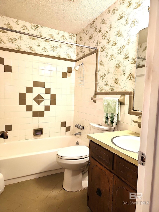 full bathroom with toilet, tiled shower / bath, a textured ceiling, vanity, and tile patterned flooring